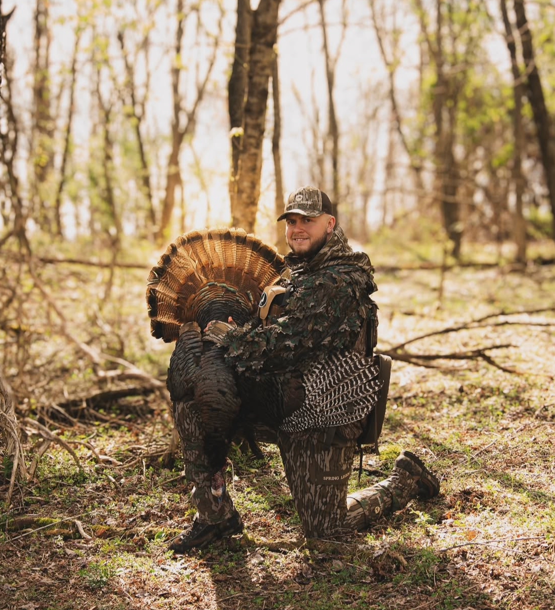 Person holding a turkey in a forest setting