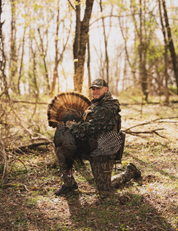 Person holding a turkey in a forest setting