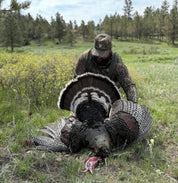 Hunter with a large turkey in a forested area