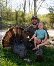 Man and child with a harvested turkey in a natural setting